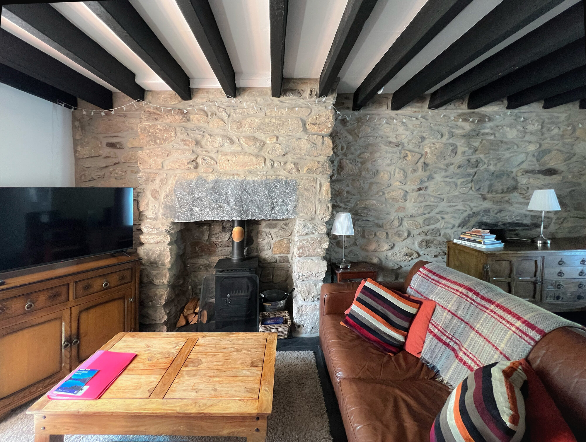 Lounge with stone wall and fireplace with log burner