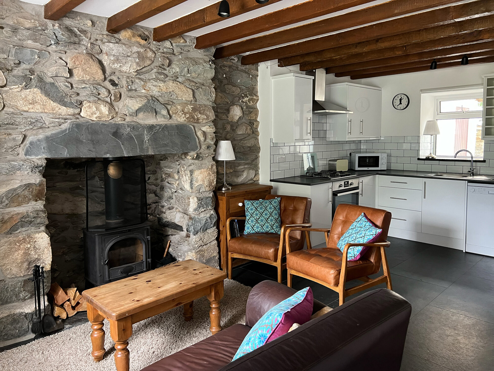 Open plan lounge and kitchen with stone fireplace and log burner